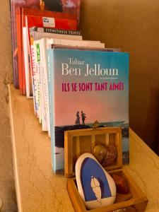 a book sitting on top of a shelf with books at Dar Dallali maison d'hôtes et excursions in Mhamid