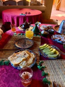a table topped with plates of food and fruit at Dar Dallali maison d'hôtes et excursions in Mhamid