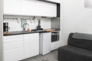 a small kitchen with white cabinets and a couch at Stunning Bright Duplex in Saint-Ouen