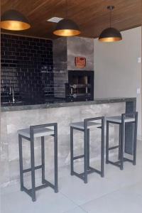 three black bar stools in front of a counter at Ks Espaço in Rondonópolis +1 photo
