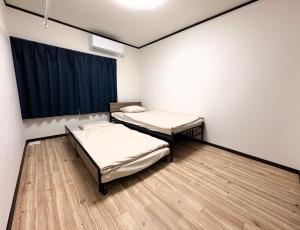 two beds in a room with a window at Frasis in Furano