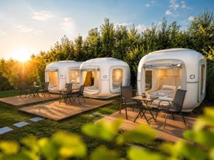 two white rvs parked in a yard with a table and chairs at Cubes am Irrsee - SELF CHECK-IN in Sommerholz