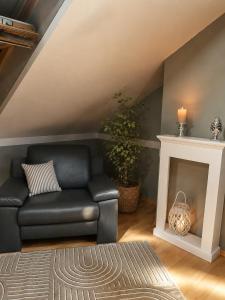 a living room with a black leather couch and a fireplace at Green Door Loft Stilvolles 160 m2 Apartment Balkon Gartenblick Workstation Hundefreundlich in Ibbenbüren