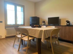 a dining room with a table with chairs and a television at Casa Felicita in Ledro