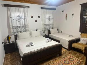 two beds in a room with white walls and windows at Guest House Iljesa in Berat +38 photos