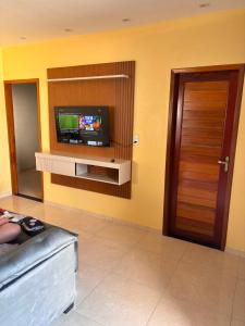 a living room with a tv on a wall at Casa Annas - Conforto e Tranquilidade in Icaraí