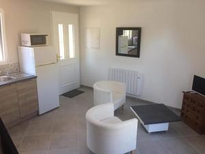 a kitchen with white chairs and a white refrigerator at Studio a la campagne in Les Bordes