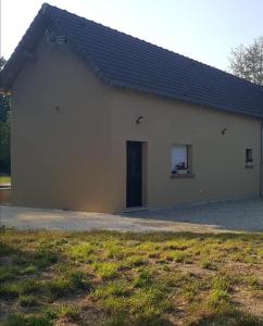 a white building with a black roof and a door at Studio a la campagne in Les Bordes