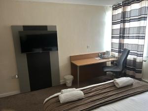 ein Hotelzimmer mit Bett, Schreibtisch und Fernseher in der Unterkunft Midland Hotel in Mansfield