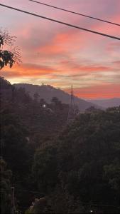 a sunset over a hill with a electricity transmission tower at Ceylan Crest in Ella +8 photos