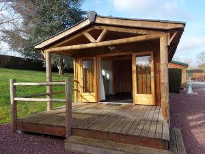 a small wooden building with a door on a deck at Camping Le Sans Souci in Fresnay-sur-Sarthe