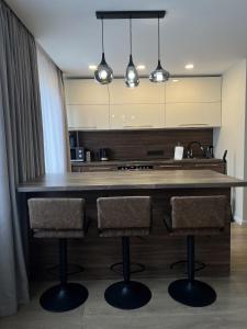 a kitchen with a large wooden island with two bar stools at Taikos apartments in Kupiškis