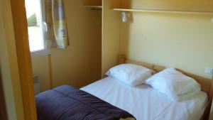 a room with a bed with two pillows and a window at Camping Le Sans Souci in Fresnay-sur-Sarthe