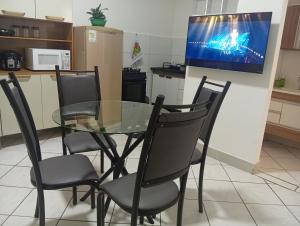 ein Esstisch mit Stühlen und ein Fernseher an der Wand in der Unterkunft Executivo central 101 in Ipatinga
