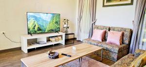 a living room with a couch and a tv at 90 9 Pool Villa Chiang Mai in Ban Pa Ngae