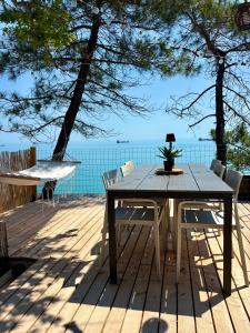 a wooden table and chairs on a deck with the ocean at AZURA one in Varna City