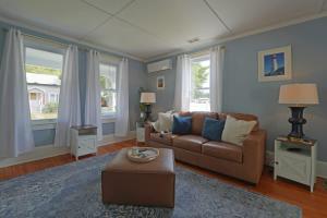 a living room with a brown couch and two windows at Beautiful Modern Beach House! in Old Orchard Beach