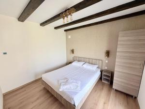 a bedroom with a white bed and a wooden floor at Casa Magda - Oaza de Relaxare in Călimăneşti