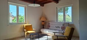 a room with two chairs and a bed and two windows at Feutres et Formes in Bourg-de-Péage