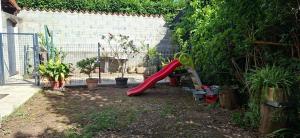 a playground with a red slide in a garden at Feutres et Formes in Bourg-de-Péage
