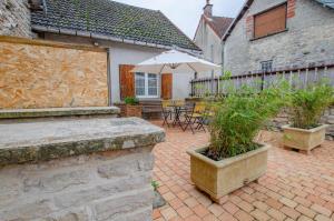 a patio with an umbrella and tables and chairs at La bulle champêtre in Balnot-sur-Laignes