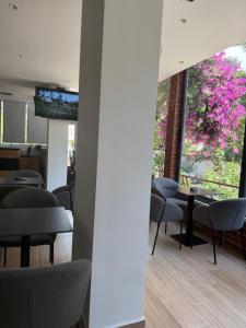 a room with chairs and tables and a window with pink flowers at Bume's Hostel in Sarandë