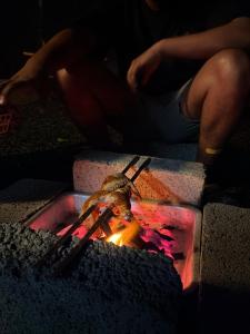 a person is sitting next to a fire at Gandhara Tent camping in Vagamon
