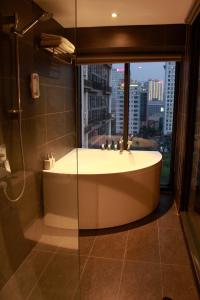 a bathroom with a bath tub and a window at Casahindout in Hanoi