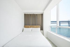 a white bed in a room with a window at 지니스테이 in Millak-tong