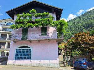 a pink building with a balcony and a blue car at Il Nido Viola in Arbedo-Castione