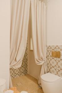 a bathroom with a toilet and a shower curtain at Treviè Suite - Torre San Giovanni in Fontanelle +97 photos