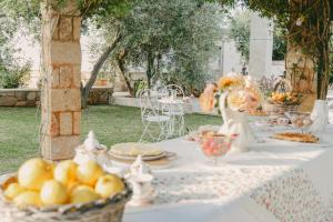 a table with a white table cloth with a bowl of fruit at Treviè Suite - Torre San Giovanni in Fontanelle