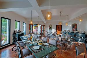 ein Restaurant mit Tischen und Stühlen in einem Raum in der Unterkunft 8fold-Pinecrest By LaRiSa, Bhimtal in Bhīm Tāl