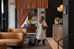 a woman is pulling a suitcase in a hotel room at Apex Waterloo Place Hotel in Edinburgh
