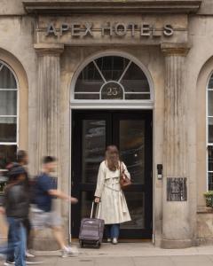 a woman is walking out of a hotel at Apex Waterloo Place Hotel in Edinburgh