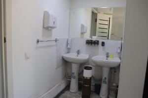 a white bathroom with two sinks and a mirror at Bulak - Kyrgyz Family Hostel in Karakol