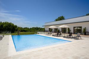 a swimming pool with chairs and umbrellas next to a building at Moinho do Canto Residence Hotel in Rio Maior