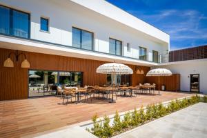 an outdoor patio with tables and umbrellas on a building at Moinho do Canto Residence Hotel in Rio Maior