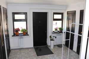 a hallway with a black door and windows and potted plants at Bulak - Kyrgyz Family Hostel in Karakol
