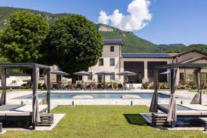 a pool with chairs and umbrellas in front of a hotel at GardaZen Suites - luxury - adults only in Caprino Veronese