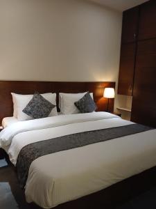 a bedroom with a large white bed with pillows at The Elet Express Luxury Hotel Apartments in Karachi