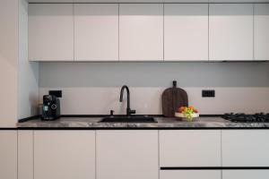 a kitchen with white cabinets and a sink at Celeste Apartment 2BDR Parking in Bucharest