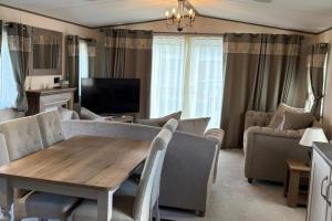 a living room with a table and chairs and a tv at 2-Bed Cabin - Sleeps 5 - Parking - Pet Friendly in Carnforth +2 photos