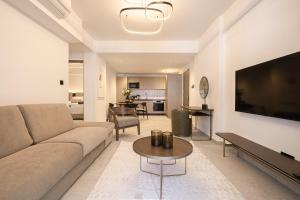 a living room with a couch and a flat screen tv at Avenue by Deserve in Paphos