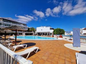 a swimming pool with lounge chairs and a resort at Teguisol Breeze en Costa Teguise in Costa Teguise