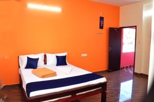 a bedroom with an orange wall and a bed at Dharani Residency in Pondicherry