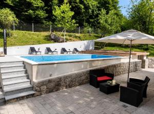 a swimming pool with chairs and an umbrella at Holiday House Marija in Otočac