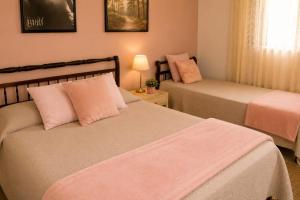 a bedroom with two beds with pink pillows at Fazenda Monte Verde a Morada do Muriqui in São Francisco Xavier +132 photos