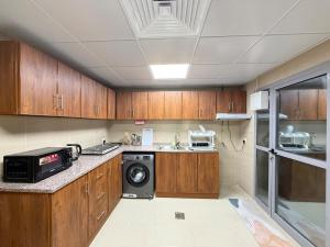 a kitchen with wooden cabinets and a washer and dryer at Unmatched Location - A Large 2BR Sea-facing Flat in Sharjah