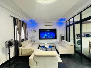 a living room with white furniture and a flat screen tv at Chez sesa in Dakar